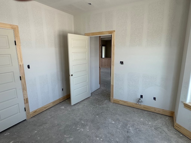 unfurnished room featuring baseboards and concrete floors