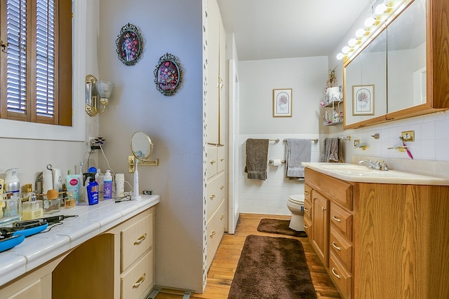 bathroom featuring hardwood / wood-style flooring, vanity, toilet, and tile walls