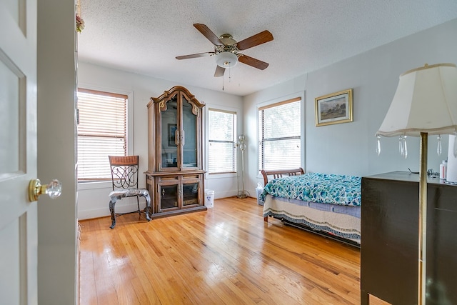 bedroom with multiple windows, hardwood / wood-style floors, a textured ceiling, and ceiling fan