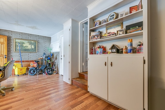 hall with brick wall, light hardwood / wood-style floors, and built in features