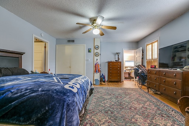 bedroom with hardwood / wood-style floors, a textured ceiling, and ceiling fan