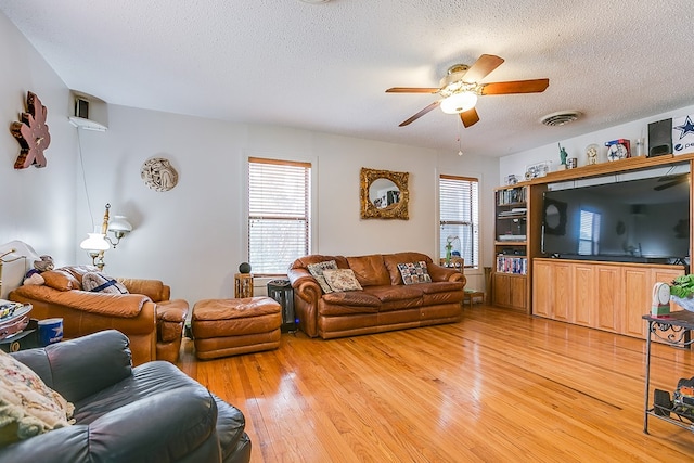 living room featuring ceiling fan, wood-type flooring, and a textured ceiling