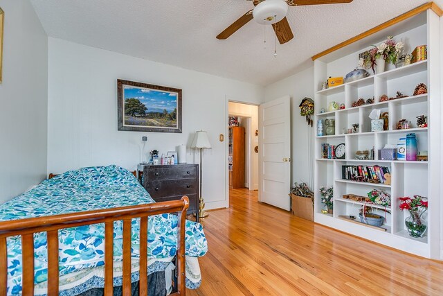 bedroom featuring light wood-type flooring, a textured ceiling, and ceiling fan