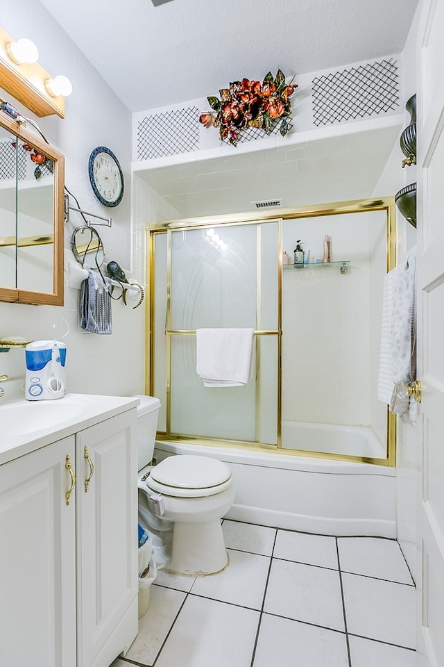 full bathroom featuring toilet, combined bath / shower with glass door, a textured ceiling, vanity, and tile patterned flooring