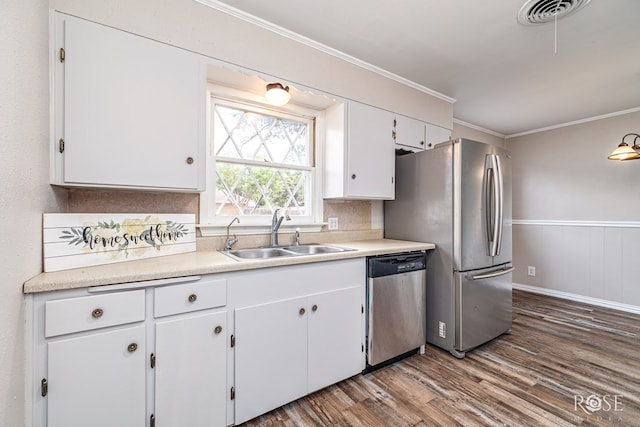 1902 College Hills Blvd, San Angelo, TX 76904 - kitchen featuring appliances with stainless steel finishes, a sink, dark wood finished floors, white cabinetry, and ornamental molding