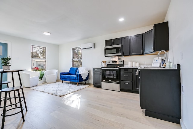 kitchen featuring appliances with stainless steel finishes, an AC wall unit, and light wood-type flooring