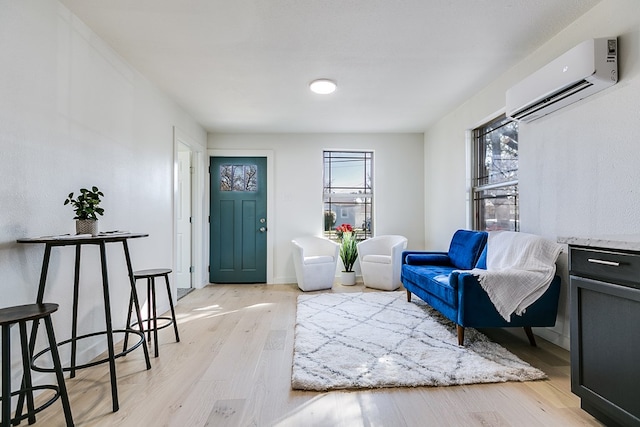 sitting room with a wall mounted air conditioner, plenty of natural light, and light hardwood / wood-style floors