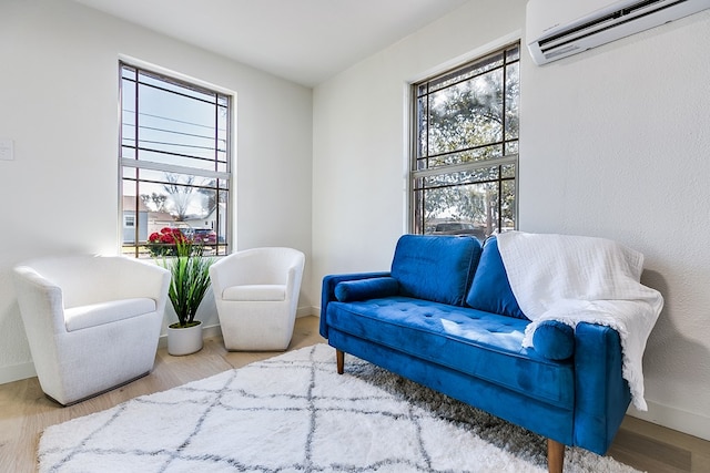 living area featuring hardwood / wood-style flooring, plenty of natural light, and an AC wall unit