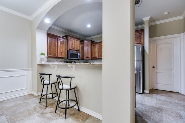 kitchen with kitchen peninsula, a breakfast bar, light stone countertops, tasteful backsplash, and appliances with stainless steel finishes