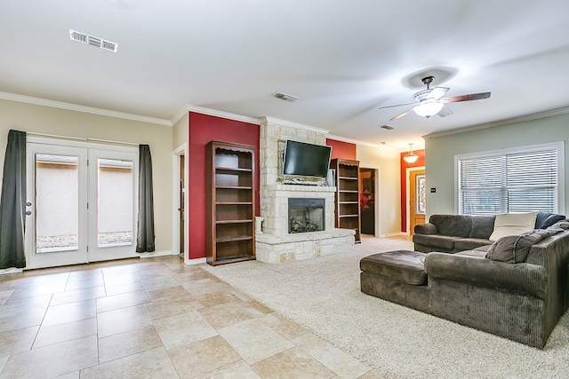 living room featuring ceiling fan, a stone fireplace, and crown molding