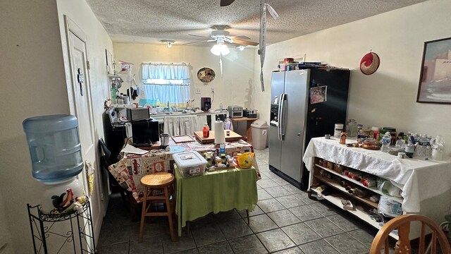 kitchen with a kitchen bar, ceiling fan, kitchen peninsula, stainless steel refrigerator with ice dispenser, and a textured ceiling