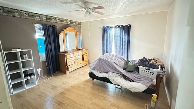 bedroom with ceiling fan, wood-type flooring, and a textured ceiling