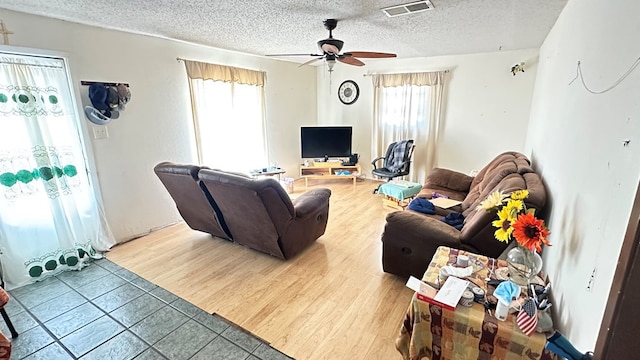 living room featuring ceiling fan, hardwood / wood-style flooring, and a textured ceiling