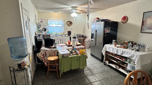 kitchen featuring a kitchen breakfast bar, ceiling fan, stainless steel fridge with ice dispenser, tile patterned floors, and a textured ceiling