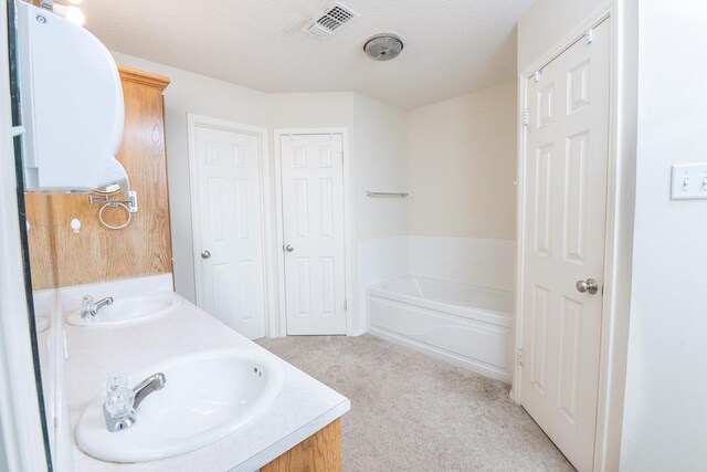 4206 Pinon Ridge Dr, San Angelo, TX 76904 - full bathroom with a garden tub, double vanity, and carpet floors