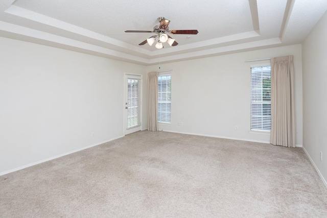 4206 Pinon Ridge Dr, San Angelo, TX 76904 - empty room featuring a tray ceiling, a ceiling fan, light colored carpet, and plenty of natural light