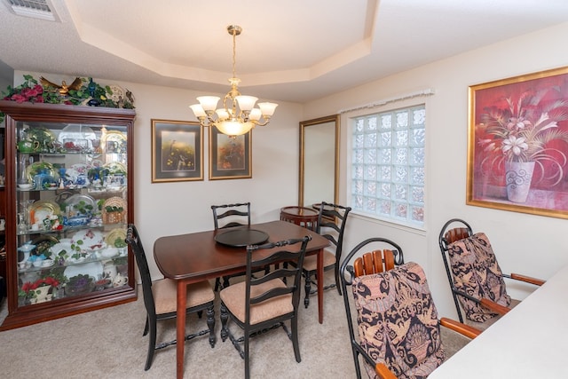 carpeted dining room featuring a notable chandelier, visible vents, and a raised ceiling
