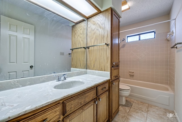 full bathroom with tiled shower / bath, a skylight, vanity, toilet, and tile patterned floors