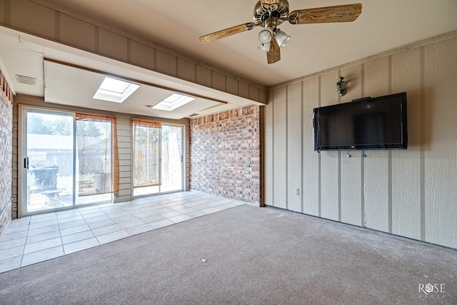 unfurnished living room featuring ceiling fan, light colored carpet, and a skylight