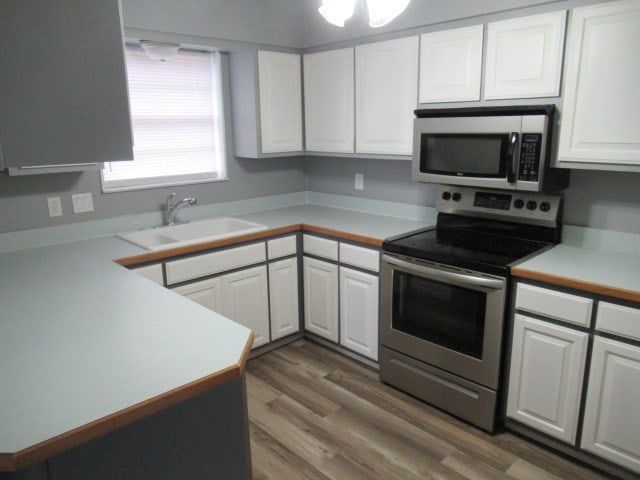 3606 Old Post Rd, San Angelo, TX 76904 - kitchen featuring stainless steel appliances, white cabinets, light countertops, and wood finished floors