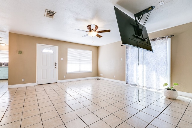 3101 Grove Dr, San Angelo, TX 76903 - unfurnished living room with a ceiling fan, light tile patterned floors, and a textured ceiling