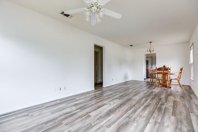 2301 W Concho Ave, San Angelo, TX 76901 - unfurnished room with light wood-type flooring, visible vents, baseboards, and ceiling fan with notable chandelier