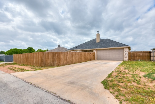 3406 Twin Mountain Dr, San Angelo, TX 76904 - view of side of property with concrete driveway, a chimney, an attached garage, and roof with shingles
