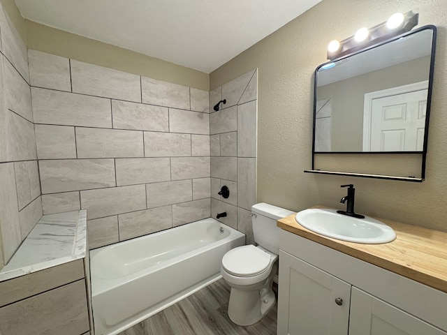 919 E 20th St, San Angelo, TX 76903 - bathroom featuring wood finished floors, vanity, washtub / shower combination, toilet, and a textured wall