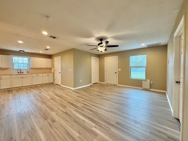 919 E 20th St, San Angelo, TX 76903 - unfurnished living room featuring light wood-type flooring, baseboards, a ceiling fan, recessed lighting, and a sink