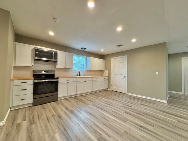 919 E 20th St, San Angelo, TX 76903 - kitchen featuring stainless steel appliances, butcher block counters, a sink, baseboards, and backsplash
