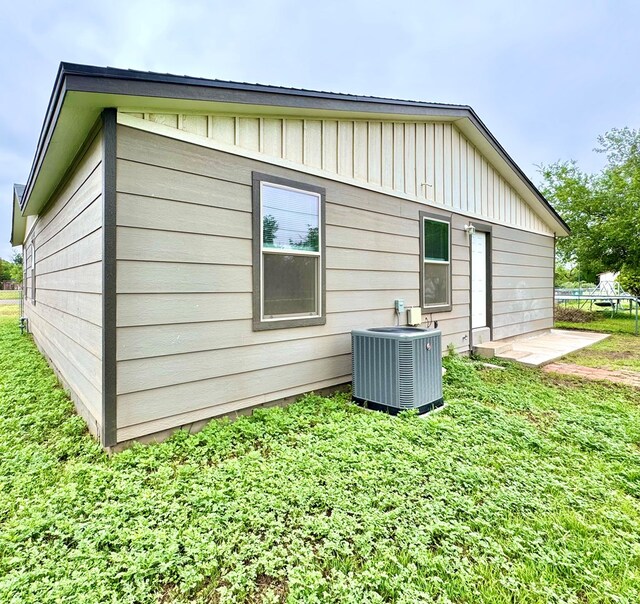 919 E 20th St, San Angelo, TX 76903 - rear view of house with central air condition unit, board and batten siding, and a lawn