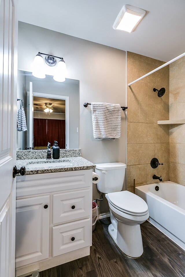 full bathroom featuring wood-type flooring, toilet, tiled shower / bath combo, and vanity