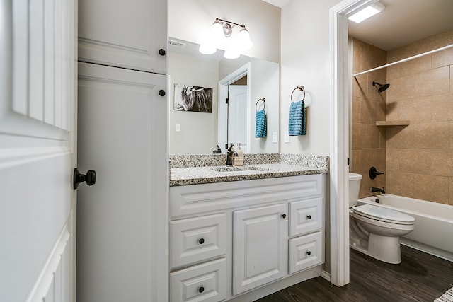 full bathroom with tiled shower / bath combo, wood-type flooring, vanity, and toilet