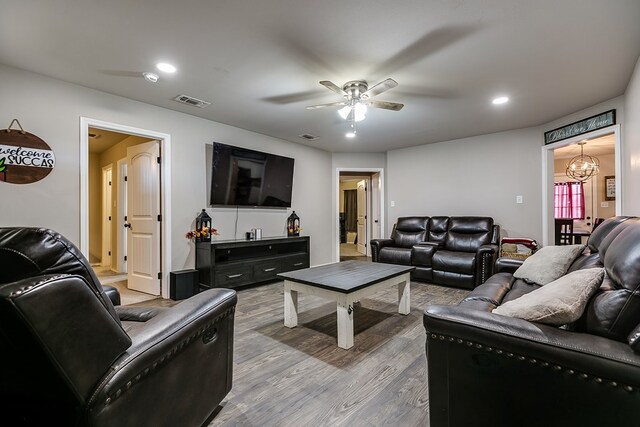 living room with hardwood / wood-style flooring and ceiling fan with notable chandelier