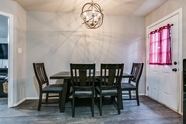 dining space with dark wood-type flooring and a notable chandelier