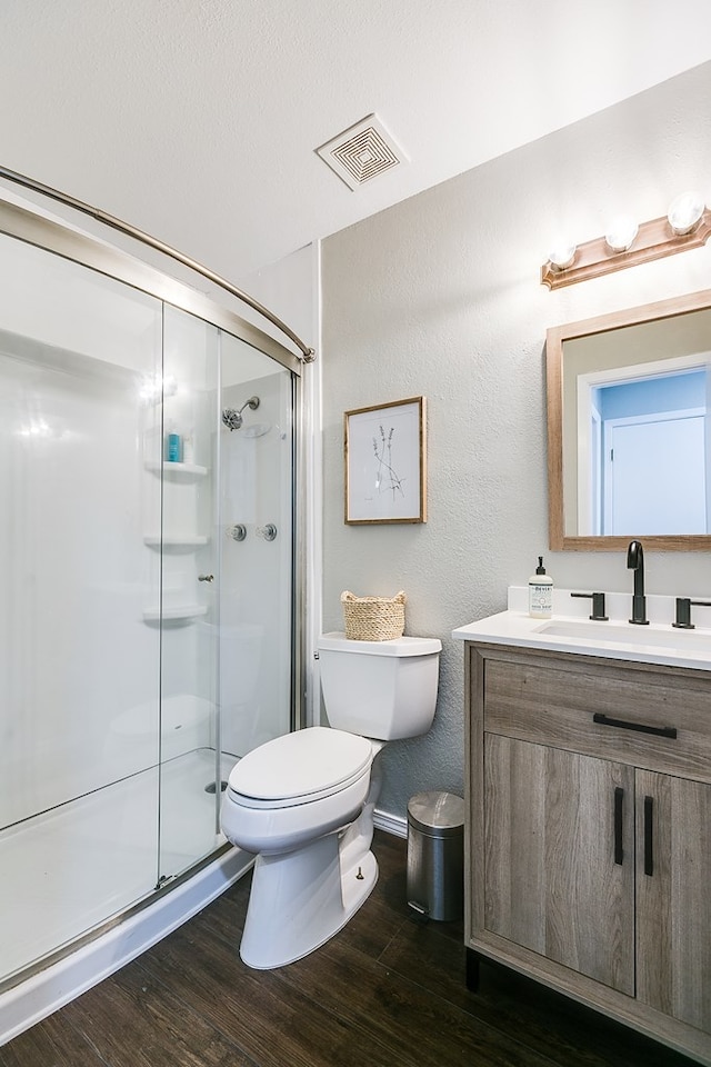 bathroom featuring walk in shower, wood-type flooring, toilet, and vanity