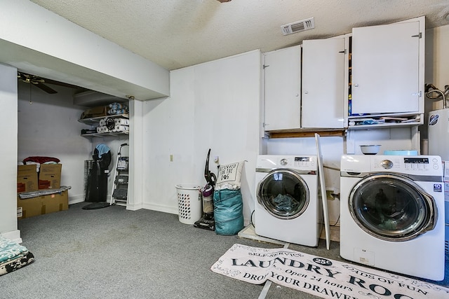 clothes washing area with cabinets, ceiling fan, washer and dryer, and a textured ceiling