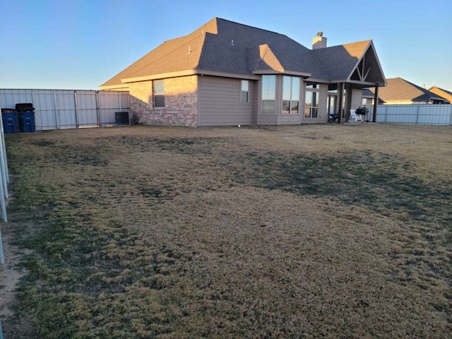 rear view of property featuring central AC and a lawn