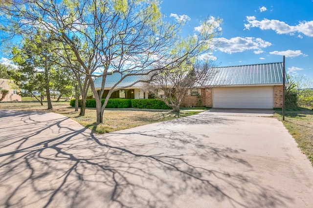 261 Edinburgh Rd, San Angelo, TX 76901 - view of front of house featuring brick siding, driveway, an attached garage, and metal roof