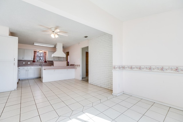 261 Edinburgh Rd, San Angelo, TX 76901 - kitchen featuring light countertops, a peninsula, island range hood, white cabinets, and ceiling fan
