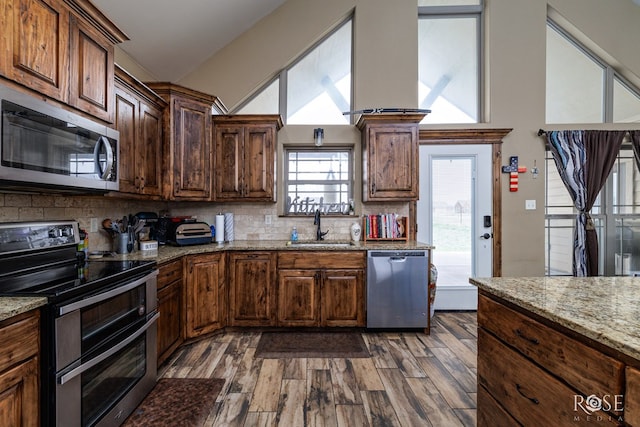 3504 Badger Ct, San Angelo, TX 76901 - kitchen with appliances with stainless steel finishes, a sink, backsplash, and dark wood-type flooring