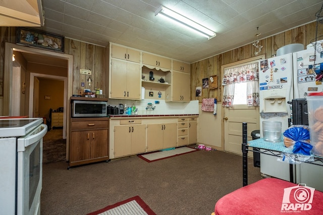 kitchen with cream cabinets, dark colored carpet, wood walls, and white electric range oven