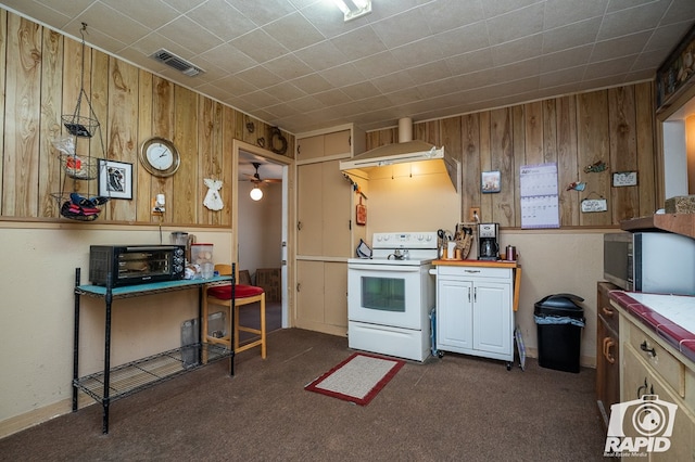 kitchen featuring wall chimney range hood, dark carpet, wooden walls, and white range with electric stovetop