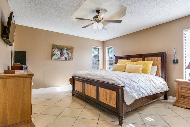 bedroom featuring light tile patterned flooring, ceiling fan, and a textured ceiling