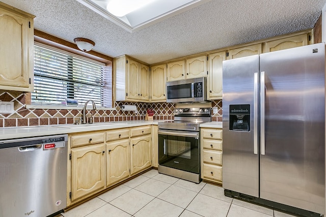 kitchen with tasteful backsplash, sink, light tile patterned floors, and appliances with stainless steel finishes