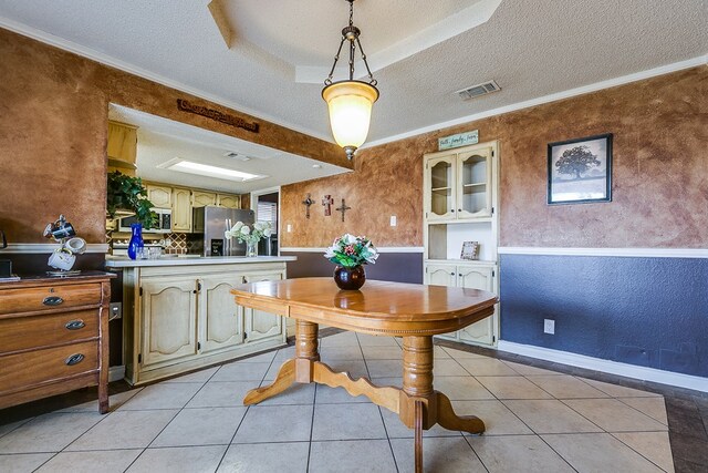 tiled dining area featuring crown molding and a textured ceiling