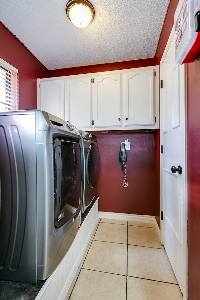 clothes washing area with cabinets, light tile patterned floors, a textured ceiling, and independent washer and dryer