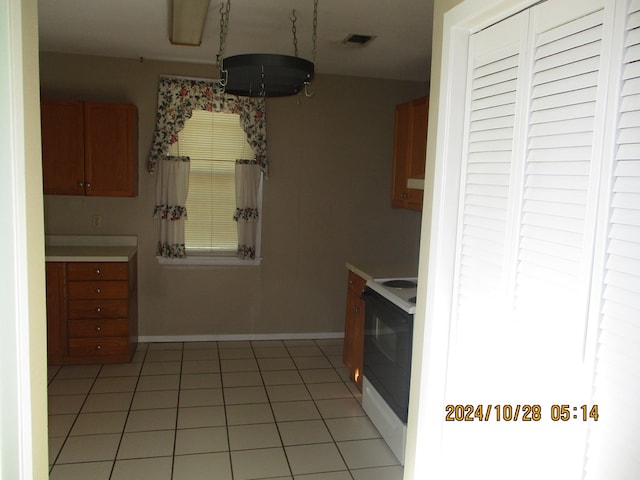 kitchen with electric stove and light tile patterned flooring