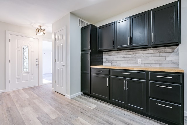 kitchen with wood counters, decorative backsplash, and light hardwood / wood-style floors