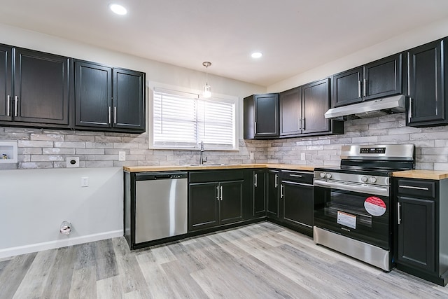 kitchen featuring sink, hanging light fixtures, light wood-type flooring, stainless steel appliances, and backsplash